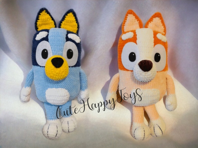 May include: Two crocheted stuffed dog toys. The blue dog has yellow ears and a yellow nose. The orange dog has white ears and a brown nose. Both dogs have big eyes and are sitting on a white surface. "Cute Happy Toys" is written in white text on the surface.