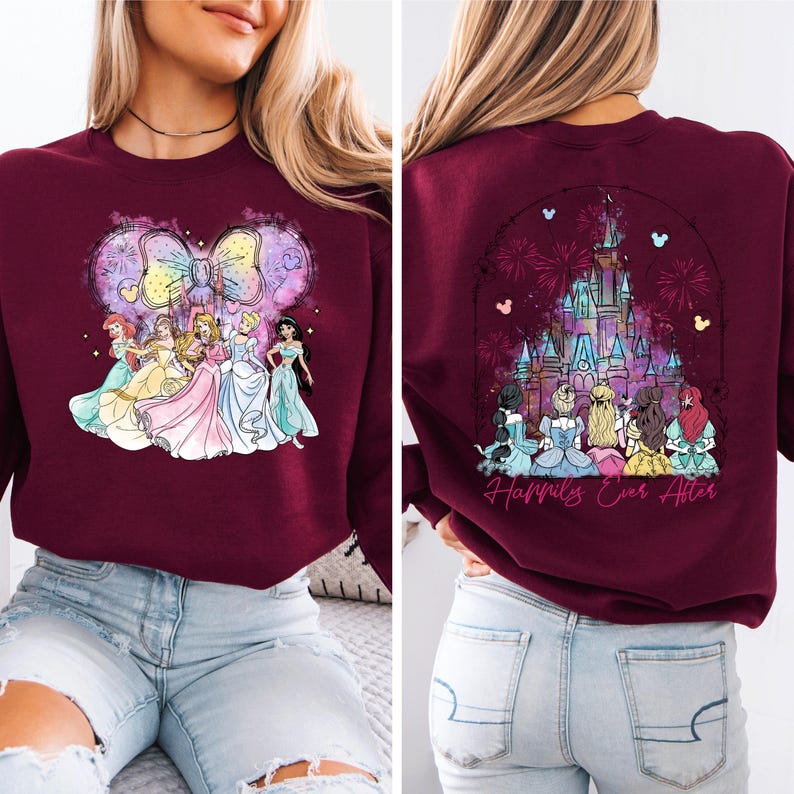 Puede incluir: Sudadera color burdeos con un gr&aacute;fico de princesas Disney frente a un lazo rosa y fuegos artificiales. La parte posterior de la sudadera tiene un gr&aacute;fico del castillo de Cenicienta con fuegos artificiales y el texto "Happily Ever After".