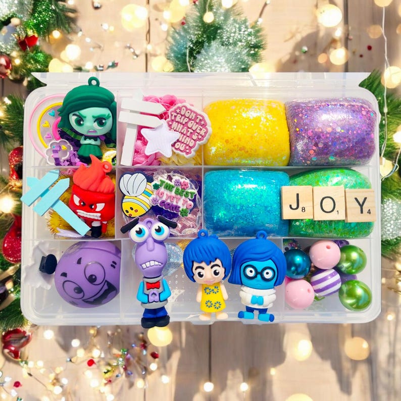 May include: A clear plastic organizer filled with colorful Inside Out themed items. Includes character figurines, glittery blocks, and decorative elements. The word "JOY" is spelled out with letter tiles. The phrase "Don't trip over what's behind you" is visible.