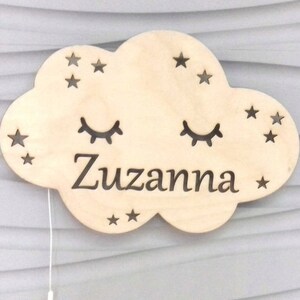 Può includere: Un'illuminazione notturna in legno a forma di nuvola con un design a taglio di stelle, occhi e il nome "Zuzanna".