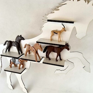 May include: White wooden horse silhouette wall shelf with five shelves. The shelves are filled with various toy animals, including horses, a gazelle, and a knight on horseback.