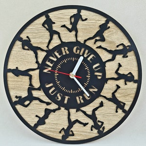 Puede incluir: Un reloj redondo negro y de madera con fondo negro y agujas blancas. La esfera del reloj tiene las palabras "Never Give Up Just Run" alrededor de la esfera. El reloj está rodeado por una silueta de corredores.
