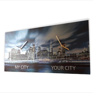 May include: A metal wall clock with a cityscape image of New York City at night. The clock has two hands, one white and one gold. The clock face has the words "My City" and "Your City" printed on it.