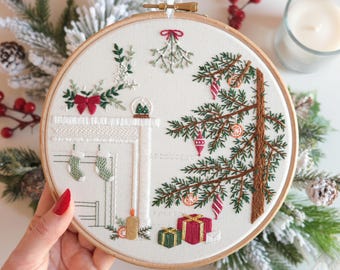 May include: Embroidered Christmas scene in a wooden hoop. The design features a Christmas tree, fireplace with stockings, gifts, and mistletoe. The color palette includes green, red, and cream. The embroidery is detailed and festive, perfect for holiday decor.