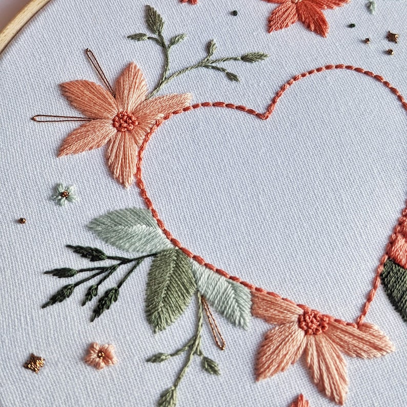 Beautiful embroidered heart design kit featuring a variety of flowers in soft pastel green and pink with copper accent details. French knots, satin stitch, back stitch, lazy daisy stitch. Fashion-led chic minimalist style with detailed decoration