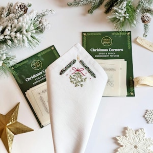 Christmas Corners Stick and Stitch embroidery patches. Add a handmade touch to your Christmas table decor or decoration scheme. Image shows csutomised napkin in front of two packs of patches.