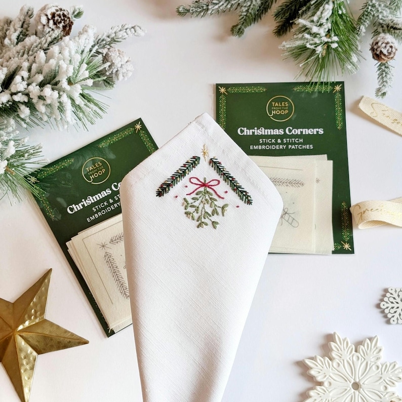 Christmas Corners Stick and Stitch embroidery patches. Add a handmade touch to your Christmas table decor or decoration scheme. Image shows csutomised napkin in front of two packs of patches.