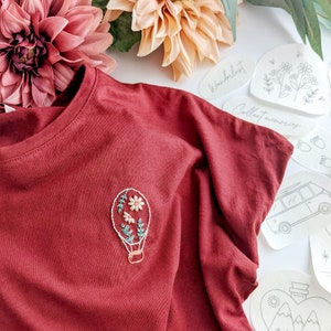 Beautiful stick and stitch embroidery design featuring a hot air balloon on a red tshirt. Escapism and embroidery combined. Easy embroidery for beginners and quick holiday projects. Make your clothes unique and add new life to your clothes.