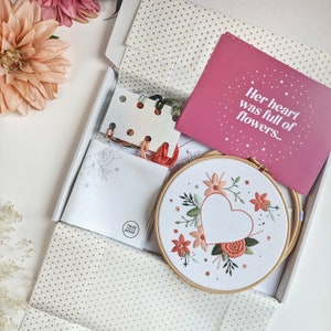 Unboxing of floral heart embroidery kit showing gorgeous and unique embroidery kit and finished hoop. Printed embroidery cotton fabric, colour card, detailed professional instructions, Elbesee embroidery hoop. Careful modern packaging.