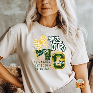 以下が含まれることがあります： クリーム色のTシャツ。黄と白のチェック柄のリボン、テキスト「MISS OUR」、番号1の緑の手、「IT'S A GOOD DAY TO BE A GREEN WAVE」のテキストが特徴のグラフィックデザイン。
