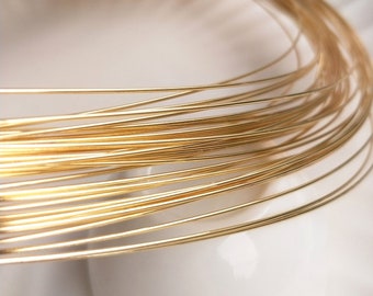 May include: Close-up of a coil of thin, shiny gold wire. The wire is tightly wound, creating a circular shape. The gold color is bright and reflective, suggesting a jewelry-making material.