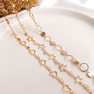 May include: Three gold chains with different charms. The top chain has round gold charms, the middle chain has star charms, and the bottom chain has heart charms.