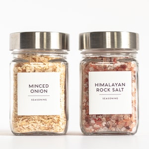 May include: Two glass jars with silver lids filled with dried minced onion and Himalayan rock salt. Both jars have white labels with black text that reads "Minced Onion Seasoning" and "Himalayan Rock Salt Seasoning".