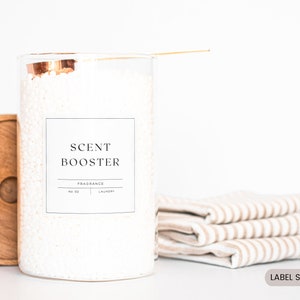 May include: A white glass jar with a copper lid filled with white laundry detergent beads. The jar has a black and white label that reads "SCENT BOOSTER" and "FRAGRANCE NO. 01 LAUNDRY". The label is 3 inches by 3 inches.