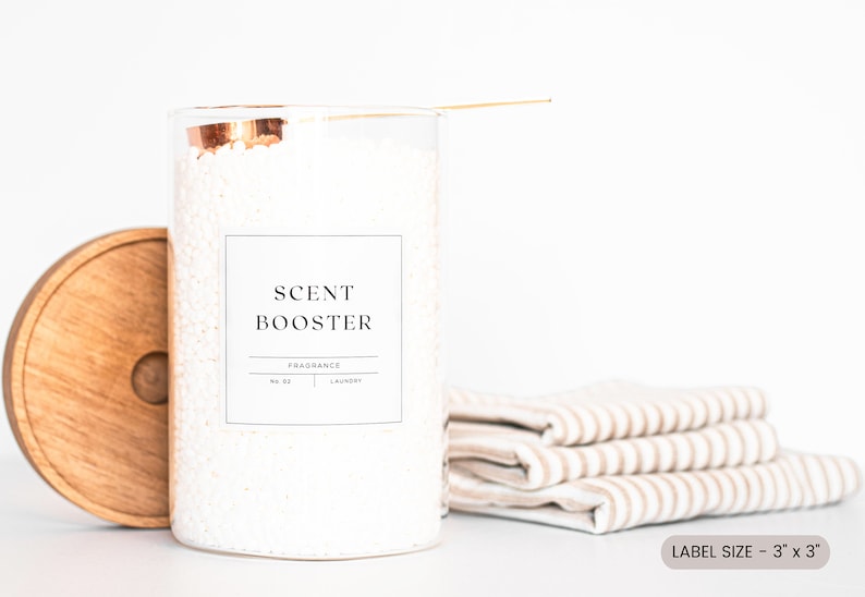 May include: A white glass jar with a copper lid filled with white laundry detergent beads. The jar has a black and white label that reads "SCENT BOOSTER" and "FRAGRANCE NO. 01 LAUNDRY". The label is 3 inches by 3 inches.