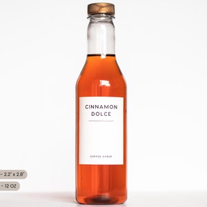 Pu&ograve; includere: Una bottiglia di vetro trasparente con un tappo marrone riempita di un liquido ambrato scuro. La bottiglia ha un'etichetta bianca con il testo "CINNAMON DOLCE" e "COFFEE SYRUP". La dimensione dell'etichetta &egrave; di 5,6 cm x 7,1 cm. La dimensione della bottiglia &egrave; di 355 ml.