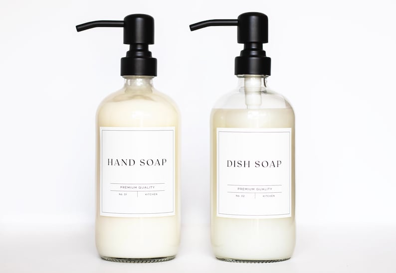 May include: Two clear glass bottles with black pump tops and white labels. The labels read "HAND SOAP" and "DISH SOAP" with the text "PREMIUM QUALITY" underneath.