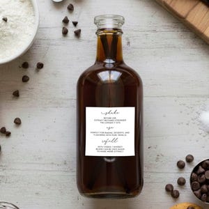 May include: A clear glass bottle filled with dark brown vanilla extract, featuring a white rectangular label with black text that reads: Shake before use. Extract becomes stronger the longer it sits. Age. Perfect for baking, desserts, and flavoring with pure vanilla. Refill. With vodka / whiskey beans can be used again to make more extract.
