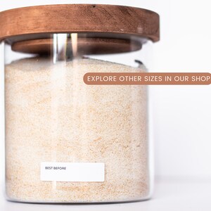 May include: A glass jar with a wooden lid filled with white grains. The jar has a label that says "BEST BEFORE" and a sticker that says "EXPLORE OTHER SIZES IN OUR SHOP".
