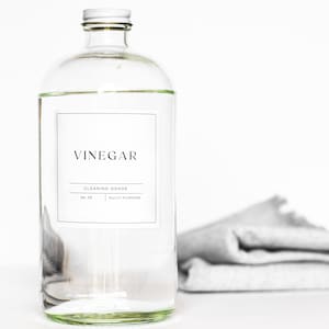 May include: A clear glass bottle with a white lid and a label that reads "Vinegar, Cleaning-Grade, Multi-Purpose".
