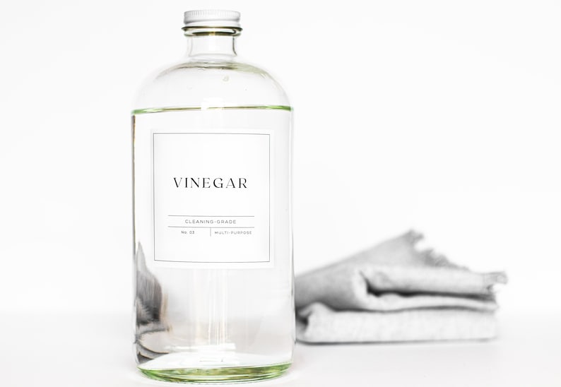 May include: A clear glass bottle with a white lid and a label that reads "Vinegar, Cleaning-Grade, Multi-Purpose".