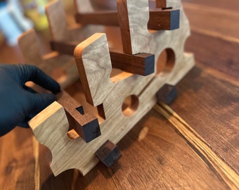 May include: A wooden wine rack with a natural wood finish and dark brown accents. The rack is designed to hold multiple bottles of wine.
