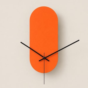 May include: A wall clock featuring a bright orange, vertically oriented pill-shaped face with rounded top and bottom edges. The clock has three thin, black hands positioned at the center, indicating the hour, minute, and second.