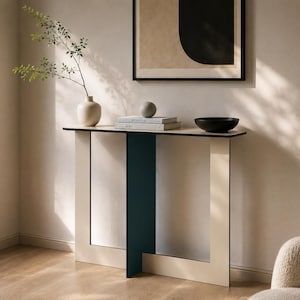 Könnte beinhalten: Ein moderner Konsolentisch mit einem geometrischen Design in Creme und Marineblau. Auf dem Tisch befinden sich eine Vase, Bücher, eine dekorative Kugel und eine schwarze Schale. Ein abstraktes Kunstwerk hängt an der Wand darüber.