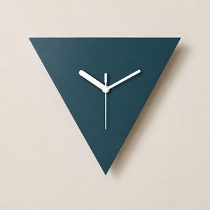 May include: A triangular wall clock with a matte dark teal face. The clock features three simple, thin white hands positioned at the center. The design is devoid of numbers or hour markers, presenting a clean, geometric shape with sharp corners.