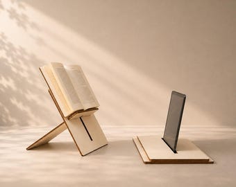 Könnte beinhalten: Zwei helle Holzständer. Ein Ständer ist angewinkelt, um ein offenes Buch mit sichtbaren Seiten zu halten. Der zweite Ständer ist flach und hält ein schwarzes Tablet aufrecht in einem zentralen Schlitz. Beide haben ein einfaches Design.