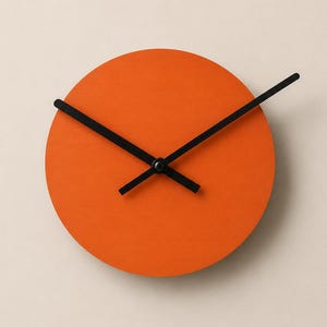 May include: A circular wall clock featuring a solid, vibrant orange face. The clock has three thin, black hands positioned at the center, indicating the time. The design is simple and lacks any numbers or hour markers on the clock face surface.