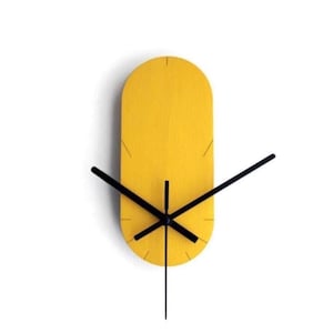 Peut inclure: Une horloge murale moderne et minimaliste. L'horloge présente un cadran ovale allongé jaune vif avec des aiguilles noires. Les aiguilles sont fines et élégantes, et l'horloge a un design simple et élégant. Une décoration élégante.