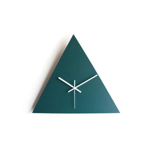 May include: A teal-colored, triangular wall clock with white hands. The clock has a minimalist design and is mounted on a white wall. The hands are positioned to indicate the time. A modern home decor item.