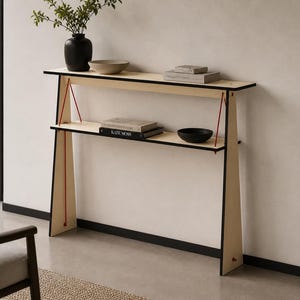 May include: A contemporary console table with two shelves, made from light-coloured wood with black edging. Red cords provide support. The table displays a black vase with foliage, a beige bowl, books, and a black bowl. The design is minimalist and modern.