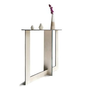 May include: A white console table with a simple, modern design. The table has a rectangular top and four legs that form an X shape. The table is made of wood and has a natural finish.