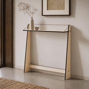 May include: A light-colored wooden console table with a slim profile, featuring black-edged side panels, a flat rectangular top surface, and a thin horizontal support bar near the base, designed with a clean, open frame structure.