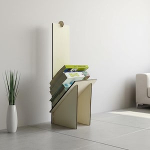 Op de afbeelding: Een moderne, lichtgekleurde houten boekenplank met een uniek stoelachtig ontwerp. De boekenplank bevat een stapel boeken en staat tegen een witte muur. Links staat een witte vaas met groene planten.