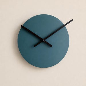May include: A circular wall clock with a matte teal face and two thin black hands. The clock face is solid and lacks numbers or markers, featuring a simple design with a central black hub connecting the hour and minute hands.