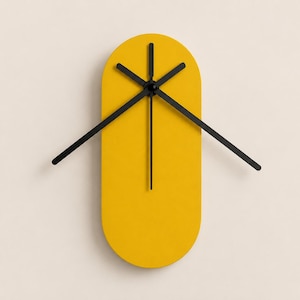May include: A wall clock with a bright yellow, vertically oriented oval face. The clock features three thin, black hands positioned at the center, with one hand pointing straight down and two others extending outward at an upward angle.