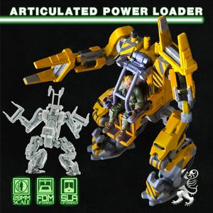 May include: A yellow and gray articulated power loader model with a seated figure inside. The model has a detailed design with hazard stripes and the text "ARTICULATED POWER LOADER". A smaller, unpainted model is also present.