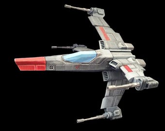 Op de afbeelding: Een grijs en rood model ruimteschip met een blauwe cockpit tegen een zwarte achtergrond. Het ruimteschip heeft twee vleugels aan elke kant, met rode strepen en accenten. De neus van het schip is rood.