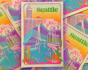 May include: A colorful illustration of the Seattle skyline with the Space Needle, a skyscraper, and a mountain in the background. The illustration is in a retro style with a purple, pink, and yellow color scheme. The text "Seattle" is printed in green letters at the top of the illustration.