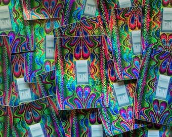 May include: A close-up of a stack of colorful, iridescent stickers with a psychedelic pattern. Each sticker features a white toggle switch with the word "ON" printed on it.