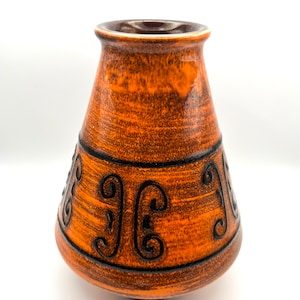 May include: A brown ceramic vase with a flared opening and a rounded base. The vase has a textured surface and is decorated with black stylised designs.