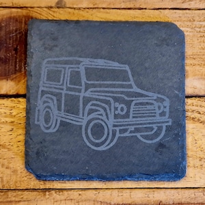 Puede incluir: Un posavasos de pizarra negra con un contorno blanco de un Land Rover Defender.