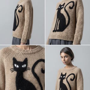 May include: A tan-colored sweater featuring a large black cat design. The cat is depicted in a sitting pose with a curved tail. The sweater has a crew neck and long sleeves, suitable for cooler weather.
