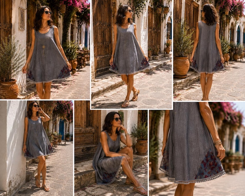 May include: A sleeveless grey A-line dress featuring a round neckline and a loose, flowing silhouette. The hem is accented with a dark floral pattern and a delicate pom-pom trim. The fabric has a subtle textured appearance throughout the garment.