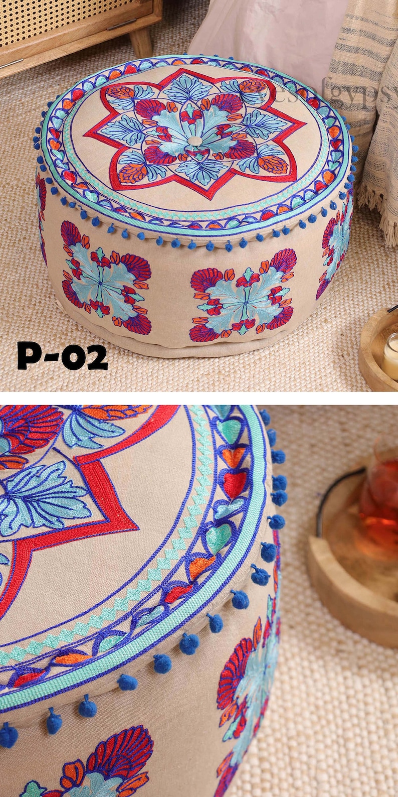 May include: A round, beige ottoman with blue pom-poms around the edge. The top of the ottoman is decorated with colorful embroidered flowers and geometric patterns.