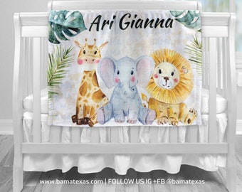 May include: A white baby blanket with a watercolor design featuring a giraffe, elephant, and lion. The blanket has the names "Ari Gianna" printed on it.
