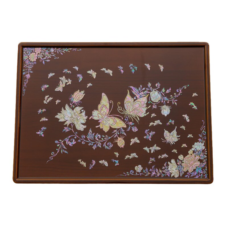 A brown lacquered table with intricate mother-of-pearl inlay of butterflies and flowers on the surface